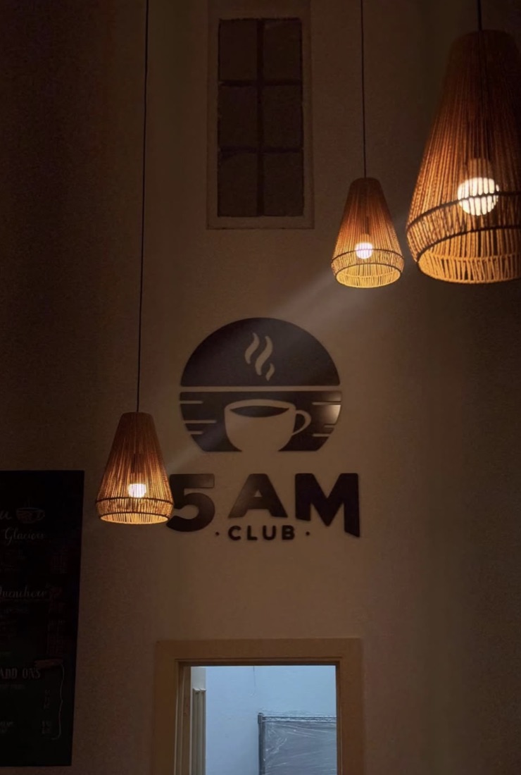 5AM Club wall sign beneath pendant lights